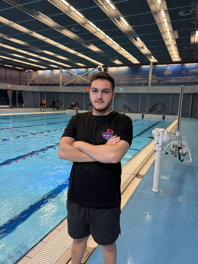 David, the coach, standing in front of the swimming pool.